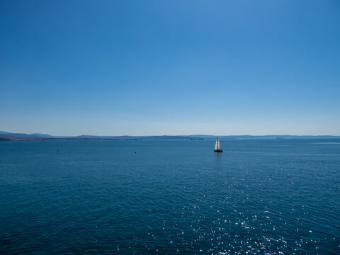 Scenic view of a sailing boat along the coastline of the golf of Trieste in Friuli-Venezia Giulia, Italy, Europe. Blue sky in tranquil atmosphere at Adriatic Mediterranean sea in summer