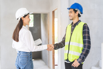 Engineer team building, teamwork contractor, two asian young partnership, builder agreement handshake plan home project contract at construction site .Happy architect, surveyor worker shaking hand.