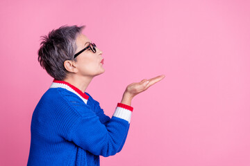 Photo of nice aged lady arms send air kiss empty space wear blue sweater isolated on pink color...