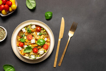 Colorful full grain fusilli pasta warm salad with feta cheese, cherry tomatoes, herbs, green pea...