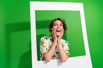 Photo of adorable thoughtful girl dressed print shirt arms hands cheeks holding paper frame empty...