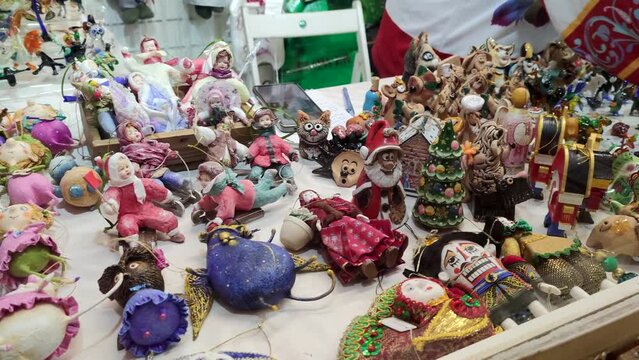 Group of various toys and souvenirs lies on street Christmas fair market stall in Moscow, Russia. Real time handheld video. Winter holidays gifts theme.