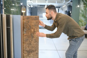 Handsome man customer choosing ceramic tile at building materials store