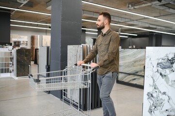 Confident male customer picking out wall tile materials for bathroom in hardware store