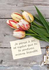 Greeting card with red, yellow and white tulips and French text: I'm thinking of you. I hope you feel better soon