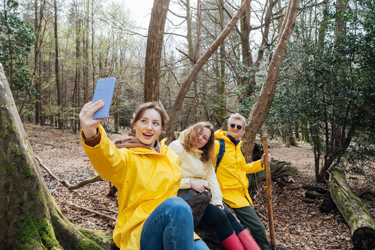 Friends taking selfies while resting during forest hiking with backpacks. Trekking travel in adventure lifestyle, nature vacation holiday with journey. Tourism, friendship concept. Outdoor activities.