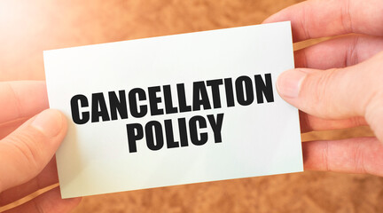 Cancellation Policy text on pale sticky note held by hand on blurry background. Personal and...