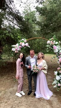 Beautiful and cheerful bride and groom pose for a photograph during an outdoor wedding ceremony in the forest. vertical video