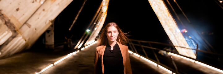 portrait of a woman walking on a bridge by night