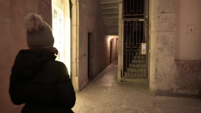 Lyon, France, December 27, 2023. Fascinating night footage of one of Lyon's traboules: the characteristic covered pedestrian walkways. A middle-aged woman walks along it.