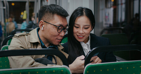 Chinese man with backpack sitting next to young girl in public transport. Traveling by train or...