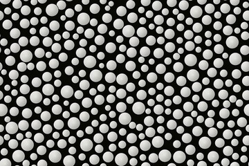 Seamless monochrome pattern with various sized white dots on a black background