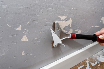 Removing silicone paint from a wall damaged by dog claws using a paint and adhesives scraper,...