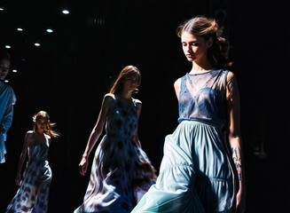 Confidence in Motion: A Woman Dominates the Runway at a Fashion Show wearing blue sexy dress  displaying a fusion of textures and styles 