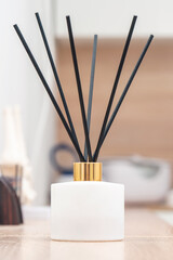 Aroma diffuser for perfumed liquid and reed sticks in the room on a wooden table