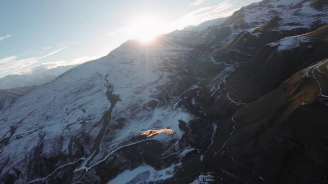 Aerial view of FPV flying behind the bird of prey Vulture. Slow motion. Chasing a wild bird in the air over the mountains at sunset. Mountains covered with snow