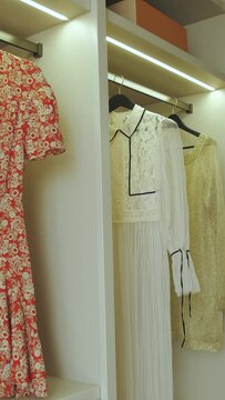Close-up Dressing room with shelves. Summer dresses hanging on shelves. Vertical video