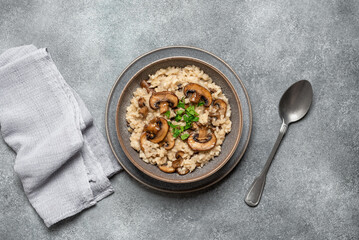 Risotto with champignon mushrooms on a gray concrete background. View from above. Italian food.