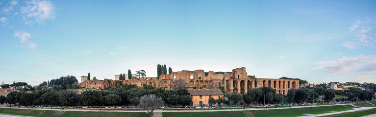 External overall view of the structures of the Roman Forum from the Circus Maximus, under a blue sky with few clouds, Rome, Lazio, Italy - obrazy, fototapety, plakaty