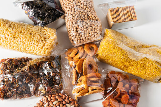 food storage, healthy eating and diet concept - close up of bags with dried fruits, cereals, pasta and nuts on white background