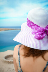 Stylish beautiful girl in hat on the seashore background