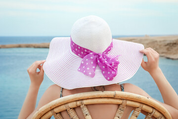 Stylish beautiful girl in hat on chair background