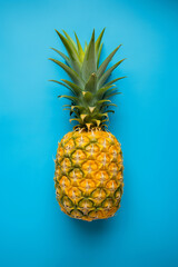 Full shot of whole raw ripe pineapple on blue background top view