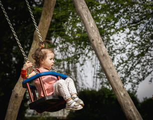 Portrait of a little girl riding on a swing. - obrazy, fototapety, plakaty