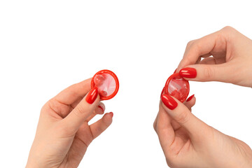 A red condom in a woman hand with red nails isolated on white background.