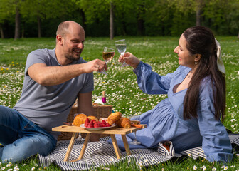 Happy pregnant couple spending time together on a picnic outdoors. They laugh merrily. They are happy. The family is expecting a child. Pregnancy. Family relationships
