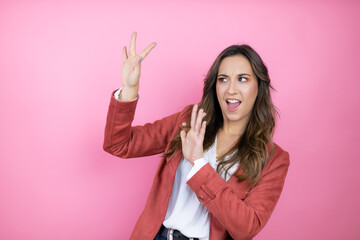 Young beautiful woman wearing casual jacket over isolated pink background scared with her arms up like something falling from above