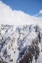 Snow-capped mountain range peaks under blue sky and white clouds, sunny day, Gergeti Trinity Church, Stepantsminda, Georgia