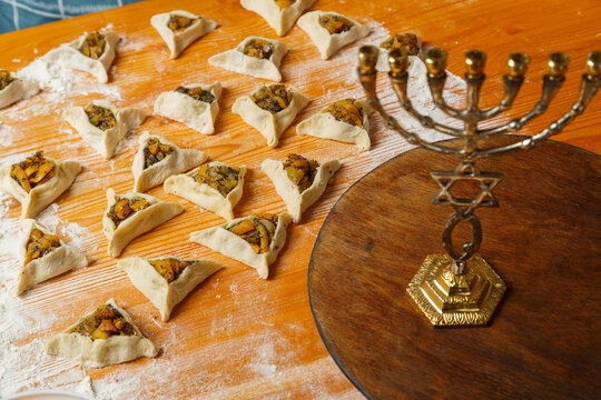 Sweet gomentashi cookies fashioned on a table next to flour and menorah