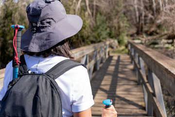 Close up of female hiker with backpack and hiking stick about to cross a nice wooden bridge in the...
