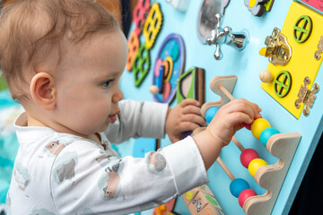 Close-up of a cute toddler playing with wooden elements on a busy board