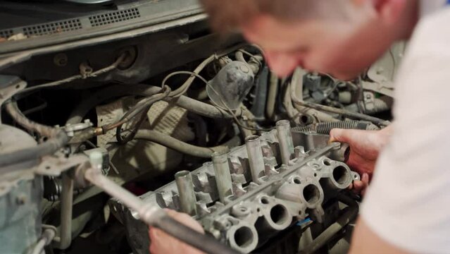 Auto mechanic installs piston rings using compressor tool in engine block at garage, demonstrates car repair, overhaul workshop process, vehicle maintenance, DIY task, engine assembly skills.