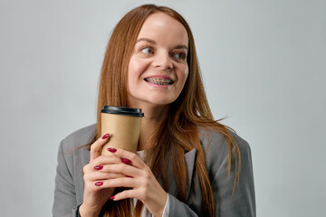 Portrait of a young European woman with braces on her teeth drinking coffee