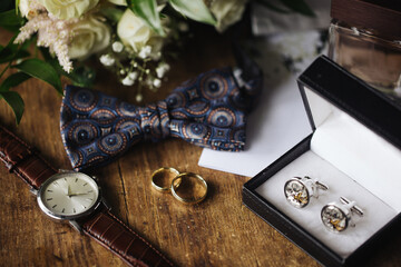 Golden wedding rings. Rustic wooden table. Buttonhole flowers. Wedding accessories background. Man...