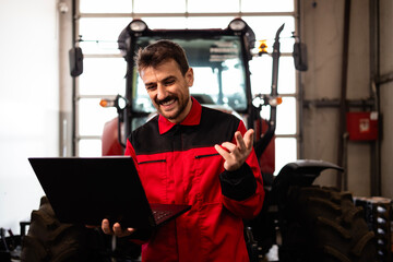 Fototapeta na wymiar Professional serviceman holding diagnostic tool and standing by the tractor.