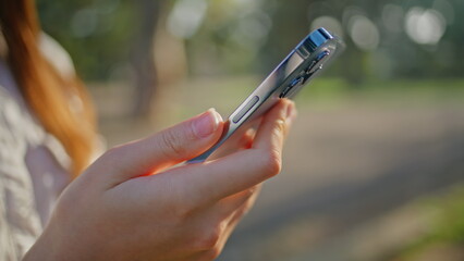 Closeup hands holding smartphone highlighting digital communication in park.