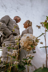 Valmiera, Latvia - August 10, 2023 - Low angle view of a smiling bride and groom standing amidst...