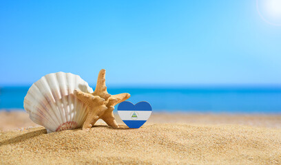 Beautiful beach in Nicaragua. Flag of Nicaragua in the shape of a heart and seashells on a sandy...