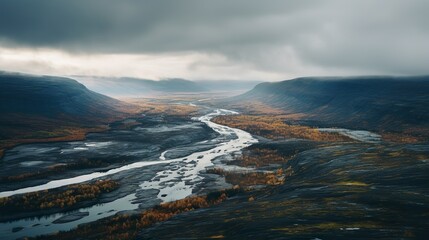 A moody, atmospheric shot capturing a winding river surrounded by a stark and sweeping cold climate valley