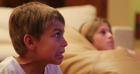 Child expression reaction in front of television screen at night young boy scared reaction