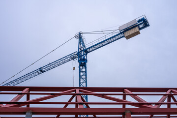 Horizontal and diagonal Geometric composition of red metal beams and a blue crane in a modern...