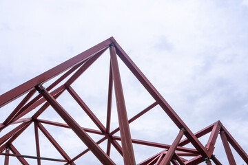 Geometric composition of red metal beams in a modern construction against a clear sky with copy...