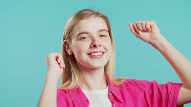Happy teenager girl dancing on blue background. Favorite music,smiling cute lady