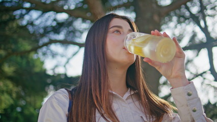 Sunlight lady enjoy drink in vibrant park closeup. Woman sipping lemon water