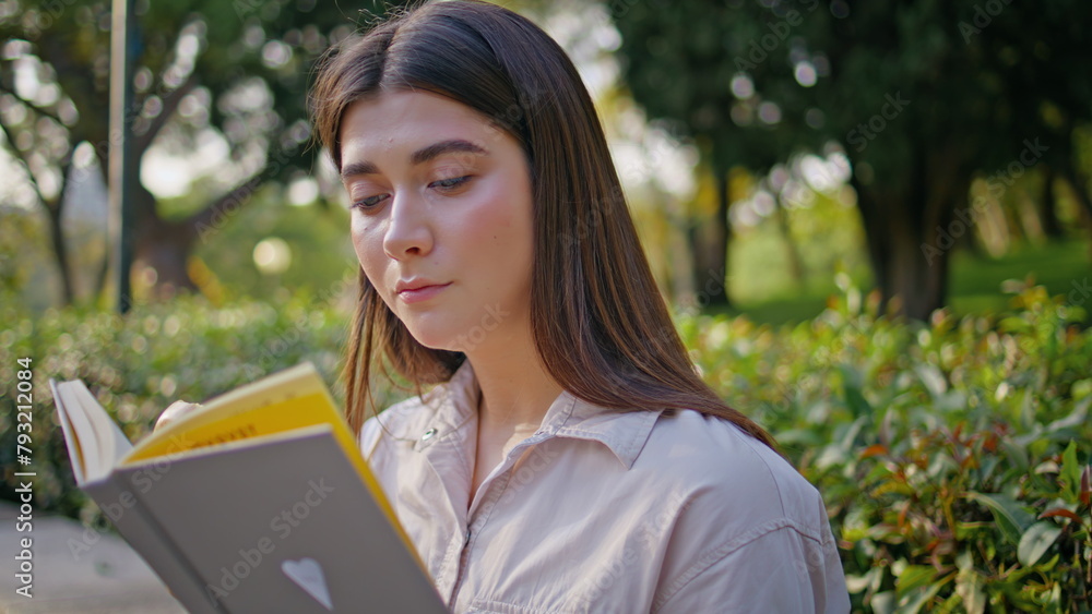 Wall mural portrait student focused reading book in sunny green garden. reader enjoying