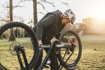 Man Inspects His Mountain Bike in a Sunny Park